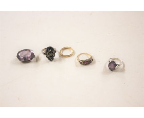 A 9ct gold wedding band; a 9ct gold ring set with ruby coloured stones; an amethyst white metal mounted brooch; and two white