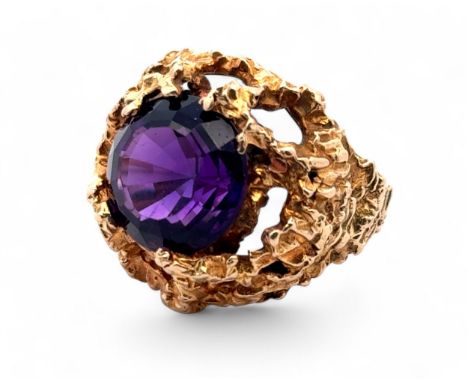 A textured gold ring set with a round step cut amethyst (12mm diameter), stamped 9ct. Size K. Weight 10.23g.