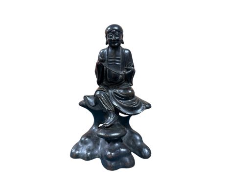 Chinese late Ming Period,Hollow cast patinated bronze figure of Lohan reading scroll,Seated on detachable rock base with pier