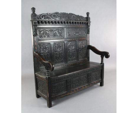 A 17th century style inlaid oak monks bench, carved with armorials and inscribed 'de bon vouloir serviar le roy', W.4ft 4in. 