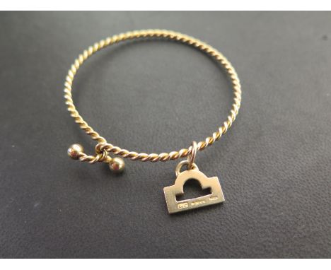 A twist torque style bangle - Tests as 9ct gold - Suspending a 9ct gold charm - Hallmarked London - Total weight approx 10.5g