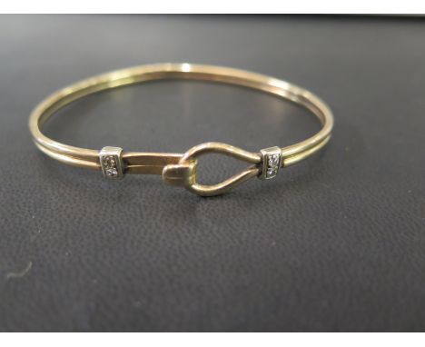 A 9ct gold diamond bangle -The grooved bangle to the brilliant-cut diamond panels and hook over clasp - Estimated total diamo