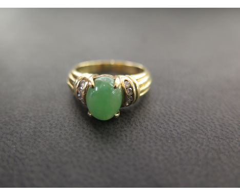 A green-gem and diamond dress ring - The oval cabochon, believed to be jade, to the brilliant-cut diamond shoulders and plain