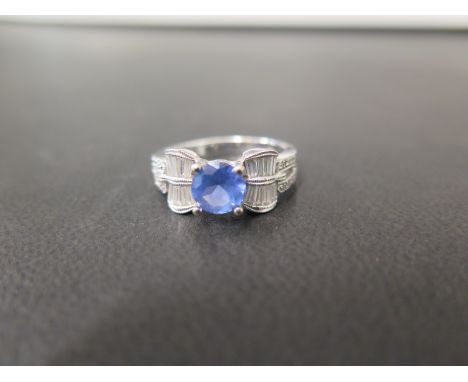 A tanzanite and diamond dress ring - The circular-shape tanzanite to the baguette-cut diamond scrolls, brilliant-cut diamond 