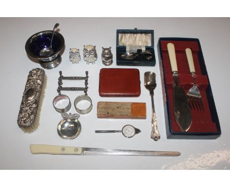 A box of various silver plated ware to include a boxed feeding spoon, cruet items, napkin rings, knife rests, a map measuring