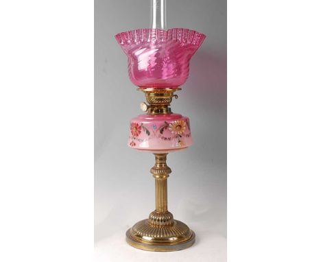 A Victorian lacquered brass and pink opaline glass pedestal oil lamp, having cranberry glass frilly and spiral fluted shade, 