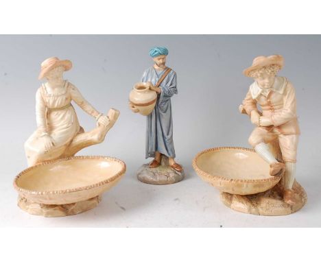 A pair of Royal Worcester figural comports by James Hadley, modelled as a boy and girl seated upon a treestump with an oval b
