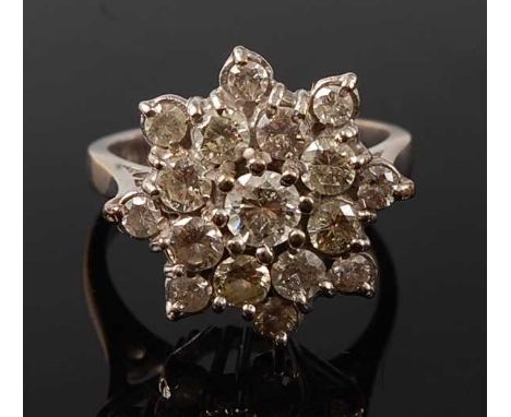 A white metal diamond circular cluster ring, featuring 17 round brilliant cut diamonds in tiered claw settings, centre diamon