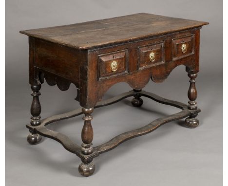 * Table. An early 18 th century oak side table, the rectangular top above three drawers each with brass ring handles, on balu