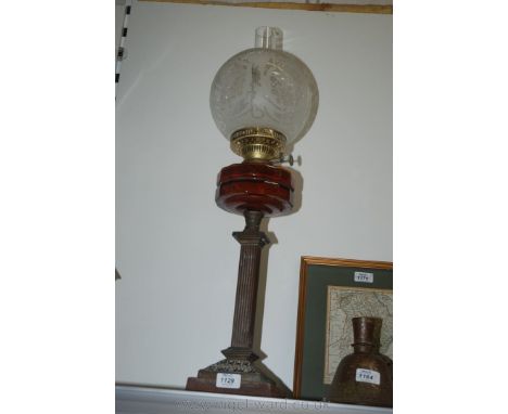 An Oil Lamp on Corinthian column with amber coloured glass reservoir, etched glass globe shade