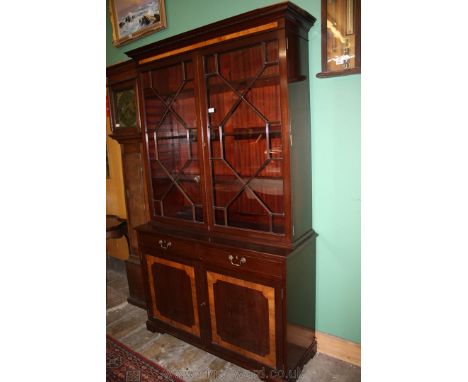 A reproduction Mahogany finished Georgian style glazed Bookcase on Cabinet having moulded cornice with castellated detail, pa