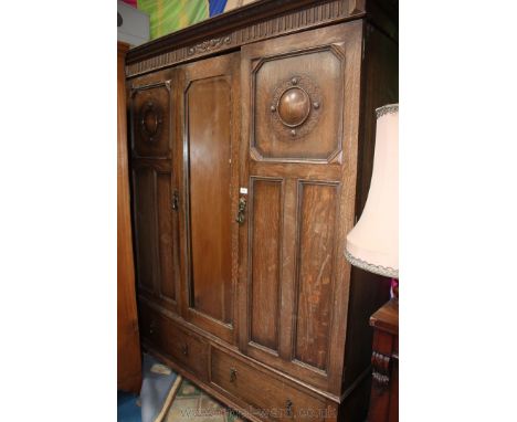 A 1930's Oak two door sectional large Wardrobe, having moulded and carved cornice over central bevel plated mirror, flanked e