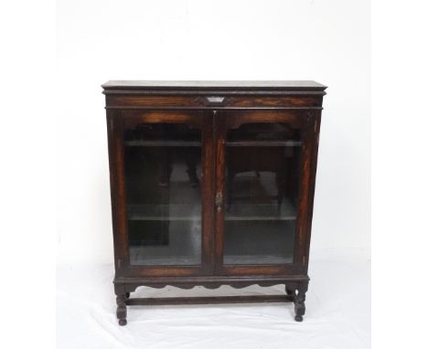 EDWARDIAN OAK BOOKCASEwith double glazed doors, adjustable shelf interior, raised on turned supports with straight stretchers