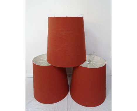 THREE LARGE TAPERING PENDANT LIGHT SHADEScovered in a terracotta coloured hessian, 80cm high x 81cm wideNote: Originally from