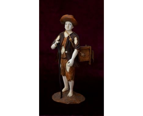 IN THE MANNER OF SIMON TROGER an 18th century German carved ivory and stained wood model of a street vendor holding a staff a