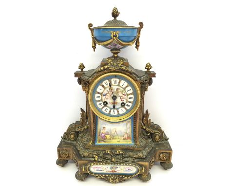 A 19th century French Ormolu cased mantle clock with Sevres style porcelain mounts, urn surmount, the dial decorated with two