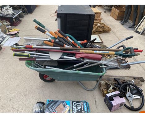 A PLASTIC WHEEL BARROW AND A LARGE ASSORTMENT OF GARDEN TOOLS TO INCLUDE SHEARS, RAKES AND SPADES ETC 