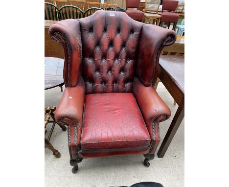AN OXBLOOD WINGED BUTTON-BACK FIRESIDE CHAIR, ON CABRIOLE LEGS 