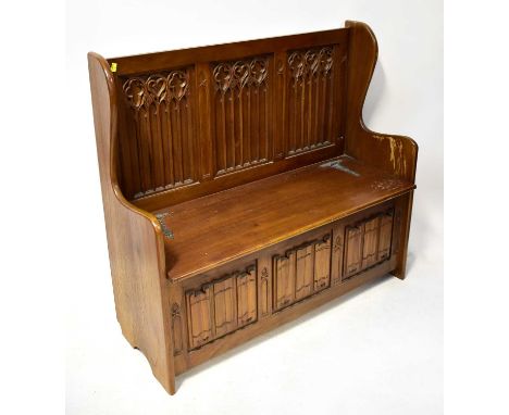 A reproduction mahogany Gothic-style bench with lift-up seat/storage, front linenfold panels, 104 x 113 x 45cm.