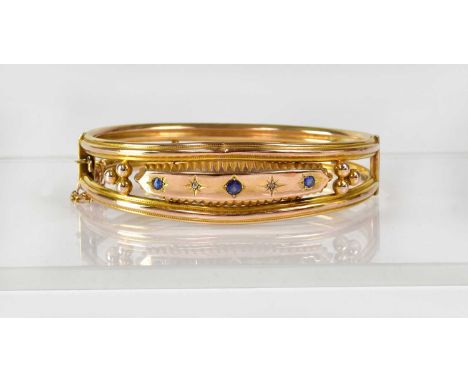 A 9ct gold bangle with double reeded band set with central panel, with two diamonds in star cut mounts and three blue gemston