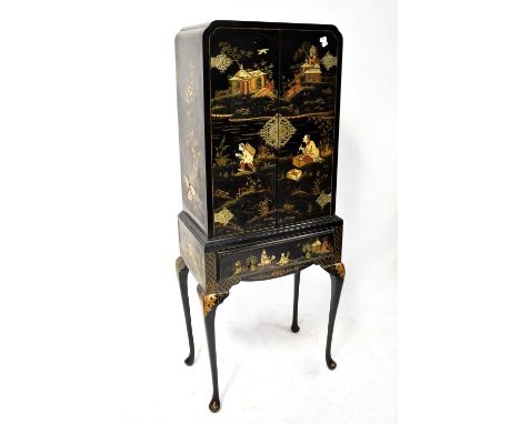 A Japanned drinks cabinet/cupboard, the front decorated with figures in a traditional landscape, with interior glass shelves 