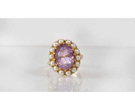 A 9ct gold cluster ring set with central oval amethyst in a surround of fourteen seed pearls in claw fittings, in scroll moun