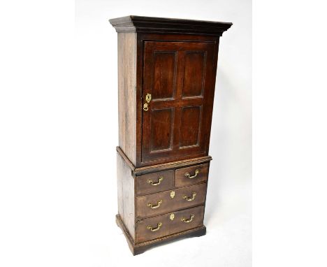 An 18th century oak cupboard on chest of narrow proportions, the moulded cornice above fielded panel single door, and two sho