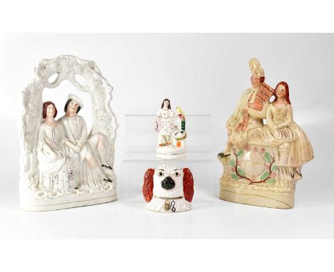 Four Staffordshire figures, including a courting couple beneath an arch, a couple sitting on a clock, a money box in the form