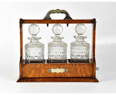 An oak tantalus with silver plated mounts, containing three square form glass decanters, height 33cm.Condition Report: The ta