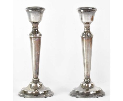 A. T. CANON LTD; a pair of Elizabeth II hallmarked silver candlesticks of tapering form, raised on circular stepped feet, wit