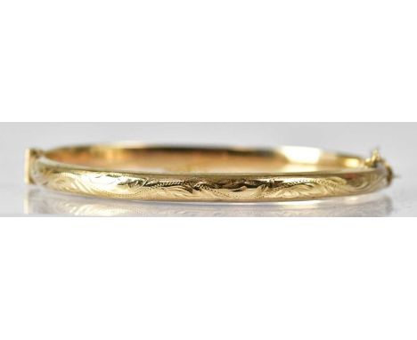 A 9ct yellow gold bangle with foliate design, with safety chain, approx. 7.8g.  Condition Report: Stamped '375' to interior. 