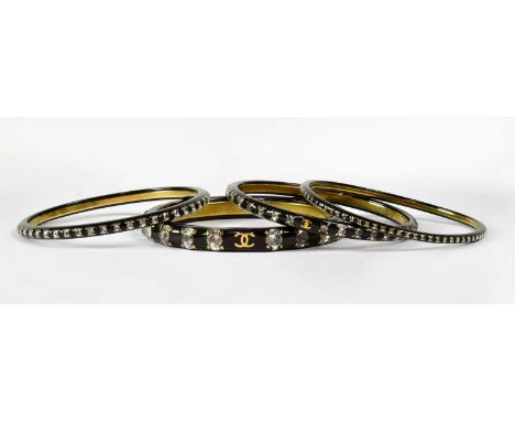 CHANEL; a black resin bangle set with diamanté and double C logo in gold plate, stamped to interior, together with three othe