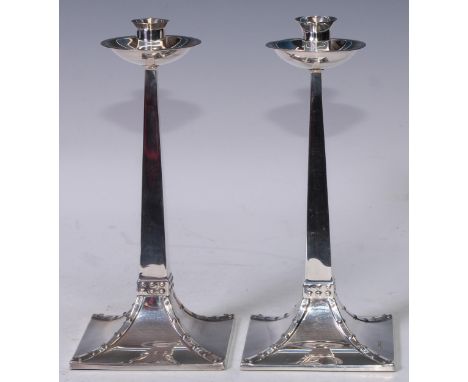 An Arts and Crafts style silver candlestick, dished circular drip pan, sreading square base with faux-rivetted borders, 22.5c