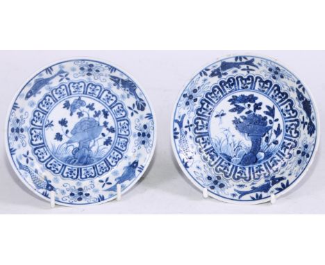 A pair of Chinese circular dishes, painted in tones of underglaze blue with flowers and rocks, within a band of lotus lappets