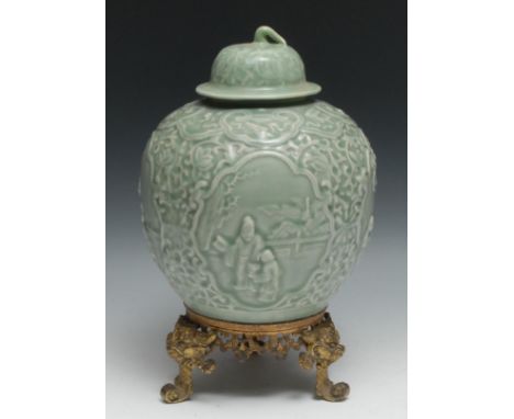 A Chinese celadon ovoid wine jar and cover, moulded in relief with four reserves of traditional figures below a ruyi frieze, 