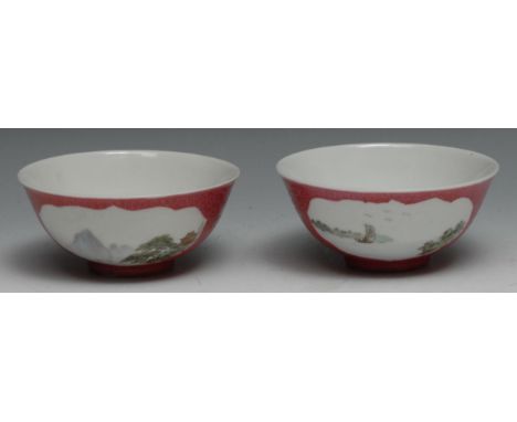 A pair of Chinese circular bowls, sparsely painted with landscapes, within shaped reserves on a rose ground incised with scro