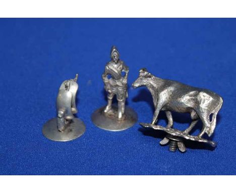 THREE SMALL WHITE METAL FIGURES
including a figure of a cow likely used as a finial on a trophy cup or similar, a figure of a