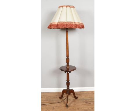 A mahogany standard lamp with central platform shelf on tripod base. Height without shade 178cm.