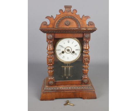 An antique Victorian walnut mantle clock, with carved case and column front, Roman numerals dial, height 44cm.  With key and 