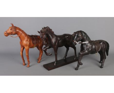 Three horse figure statues, comprising one wooden carved with a base and two vintage leather wrapped figures, measuring W35xH