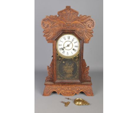 A 19th Century American "Gingerbread" oak kitchen mantle clock, with carved frame, decorated glass door and Roman numerals di
