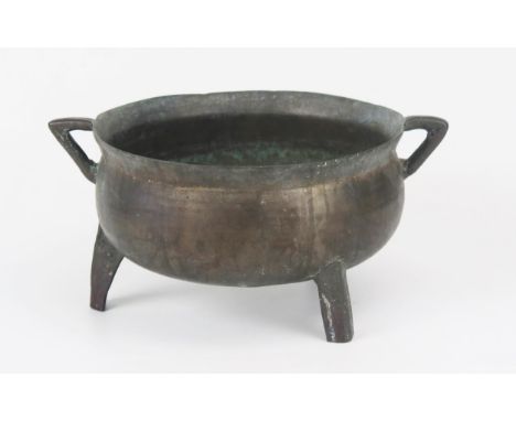 A 19th century bronze skillet, with angular loop handles and raised on three peg feet, 30cm wide.