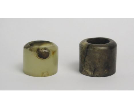 A pale jade archers ring, 2.5cm wide, together with a mottled jade archers ring. 3cm wide.