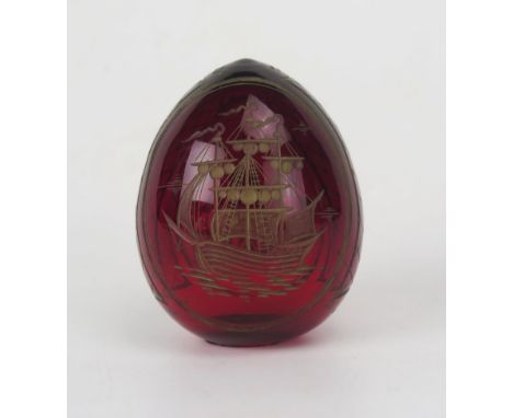 A modern Faberge ruby glass egg, decorated with a galleon and palace view, 6.5cm high.