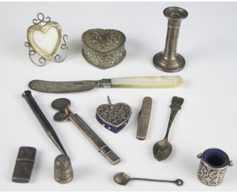 A mixed collection of silver novelties including pin cushions, heart-shaped photo frame, miniature candlestick, and other ite