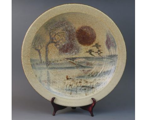 A David Eeles studio pottery charger, decorated with a rural riverside scene, impressed mark, 41cm diameter.