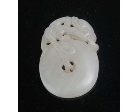 A Chinese carved pale jade pendant decorated with a mythical beast on a circular pierced disc, 5cm long.