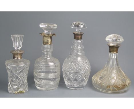 Four assorted clear glass and silver mounted decanters and stoppers, including ships decanter, thistle-shaped decanter, vario