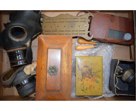 A mixed collection of items to include two WWII era gas masks, a scratch built brass cribbage board, a sarcophagus shaped tea