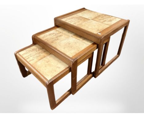 A nest of three teak tile-topped tables, width 54cm.